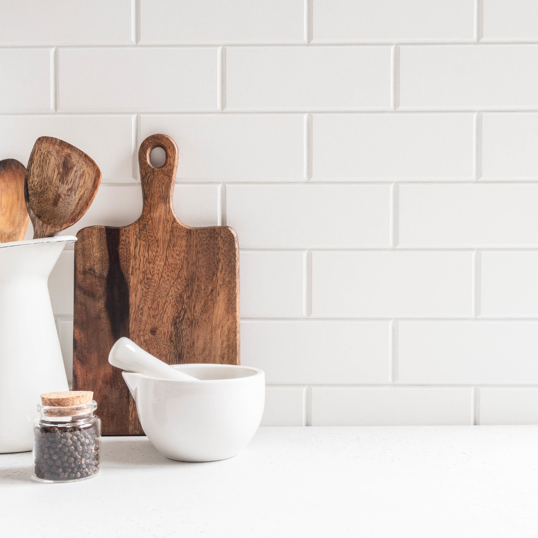 chopping board and other kitchen utensils in front of white tiles